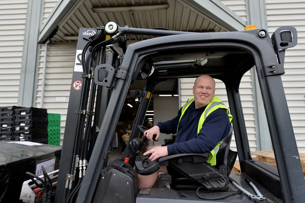 A man smiling whilst driving a forklift